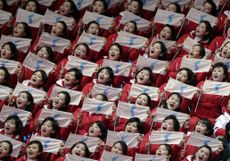 North Korean supporters hold up Korean unification flags.