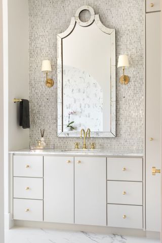 A large mirror and glittery mosaic tiles over a cream and gold vanity