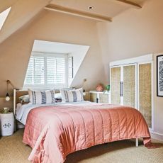 bedroom with sloping eaves with king sized bed with pink bedding