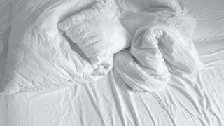 An unmade bed with crumpled duvet or comforter