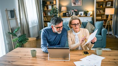 A retired couple look over retirement paperwork to check for 401(k) mistakes.