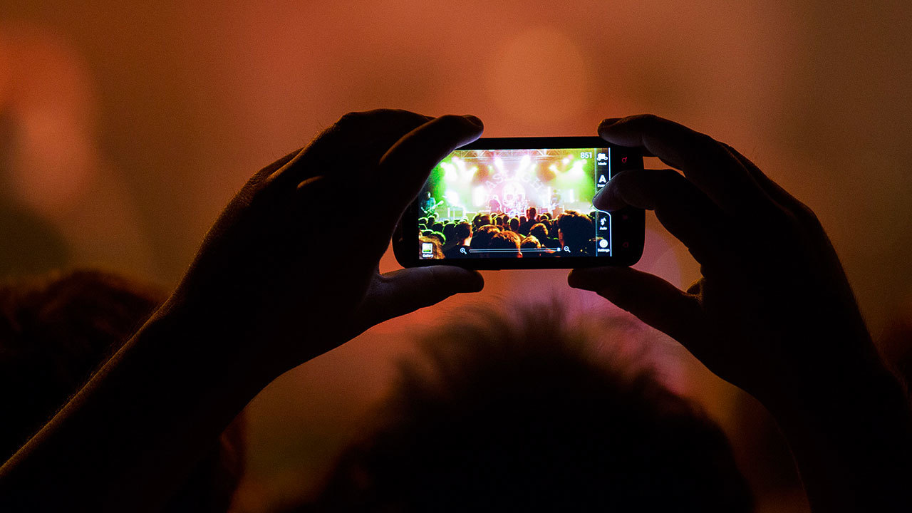 A photograph of someone holding a phone up at a gig