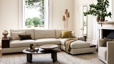 king living jasper sofa in living room with gray marle rug, black coffee table, armchair, fireplace with a vase of foliage, a window with a paddock of horses outside, and a floor lamp with three shades