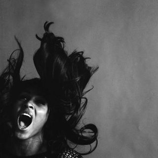 Studio portrait of American rock singer Tina Turner, wearing a dark crocheted mini-dress, singing while her long dark hair flies around her face, New York, New York, November 25, 1969.