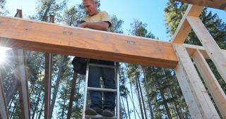 man prepares wooden roof beams