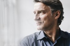 An attractive man in his 50s looks away from the camera. He appears thoughtful or concerned.