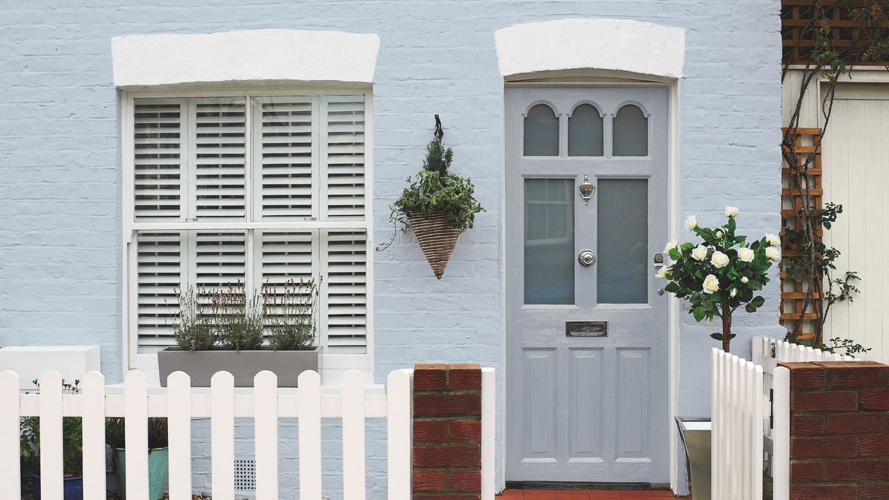 front door colour mistakes, cottage style exterior with pale blue painted masonry, pale grey walls, white picket fence 