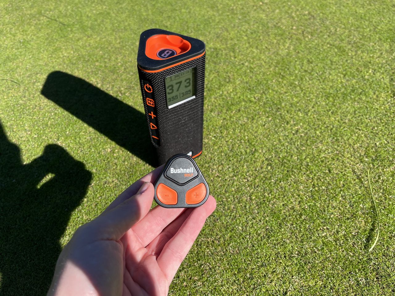 The remote in a hand next to the Bushnell Wingman View speaker