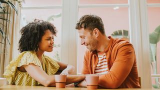 Couple sitting next to each other on a sofa in front of coffee table talking