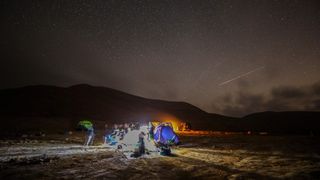 A Perseid meteor streaks across the sky above a group of campers at the Negev Desert near the city of Mitzpe Ramon, Israel, on Aug. 11, 2020. 