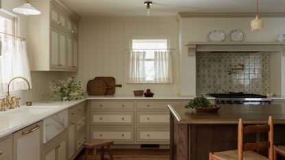 A warm neutral kitchen with vintage backsplash tiles and contrasting cabinet borders