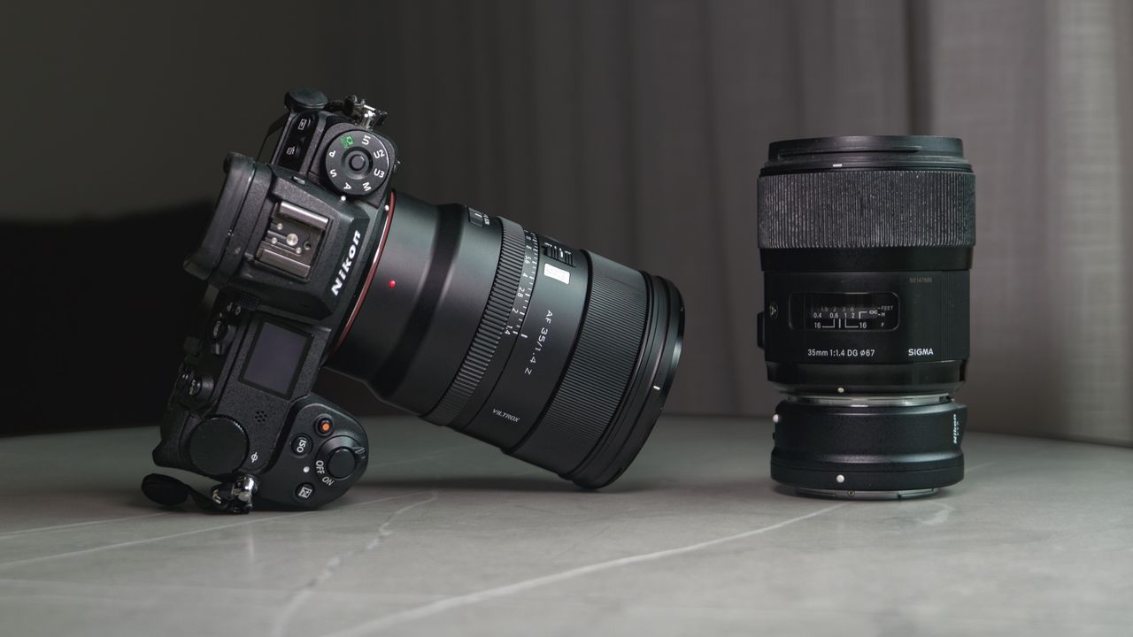 Viltrox AF 35mm F1.4 Pro lens attached to a Nikon mirrorless camera, alongside the Sigma 35mm f1/.4 DG Art lens with Nikon F to Z-mount adapter, on a white marble table