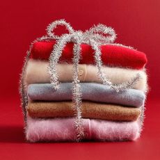 J.crew sweaters folded in a stack wrapped in silver tinsel on red background