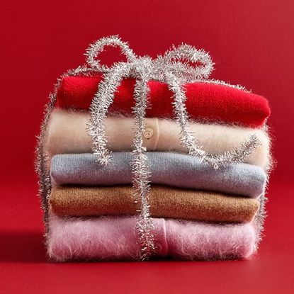 J.crew sweaters folded in a stack wrapped in silver tinsel on red background