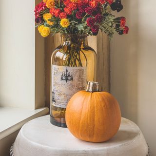 Orange pumpkin on table next to vase of flowers