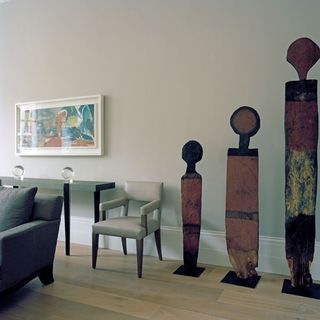 living room with white wall tall carved figures and wooden flooring