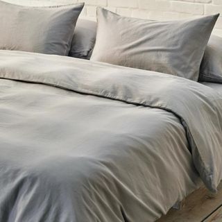 Grey bed sheets on bed in neutral room