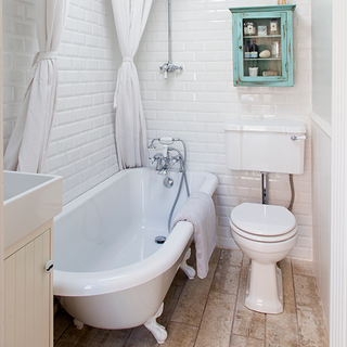 bathroom with white wall tiles and bathtub with commode