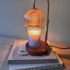 A vintage-style candle lamp on two home-style coffee table books. 