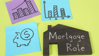 Post-it notes with a piggy bank and buildings drawn on them next to a house-shaped placard that reads "mortgage rate"
