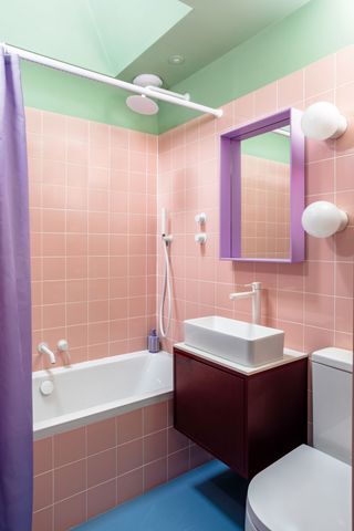 a brightly colored small bathroom in pink, purple, blue and mint green