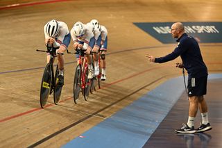 Stuart Blunt signalling to Team GB cyclists who are riding the Team Pursuit