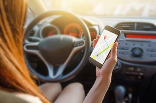 A woman uses her smartphone to navigate while driving.