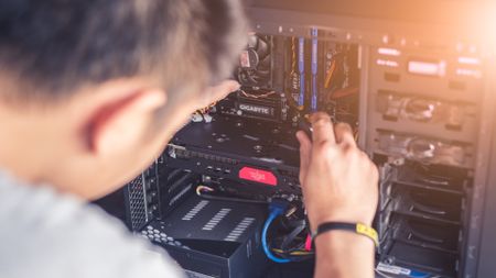 Person using a screwdriver to install a part in a PC case