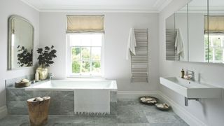 bathroom with grey stone tiles, large bathtub and natural materials