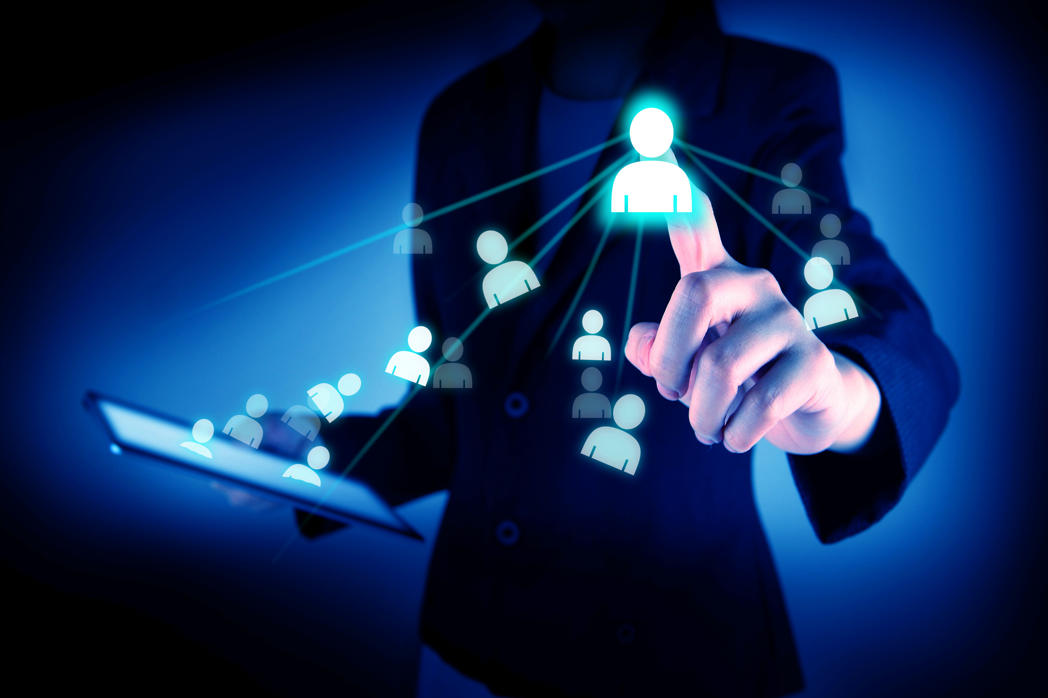 person in a suit touching digital person symbols that are floating out of a tablet