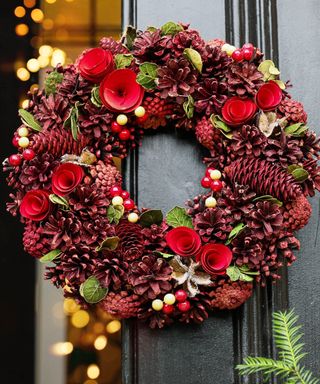 traditional pine cone Christmas wreath on a black painted front door