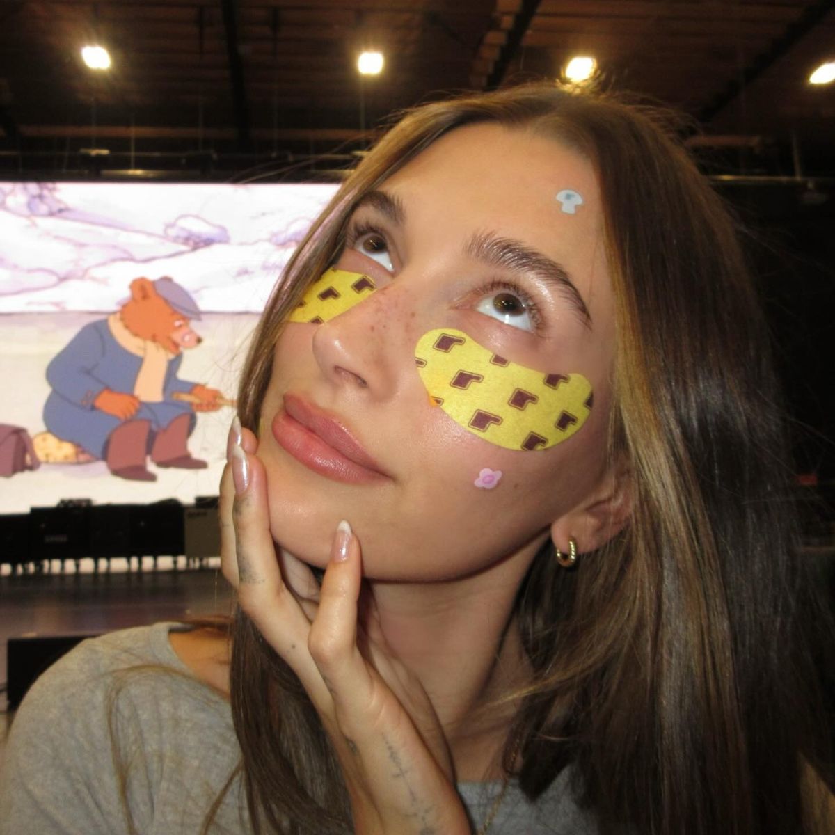 Hailey Bieber posing for a selfie wearing yellow under eye masks