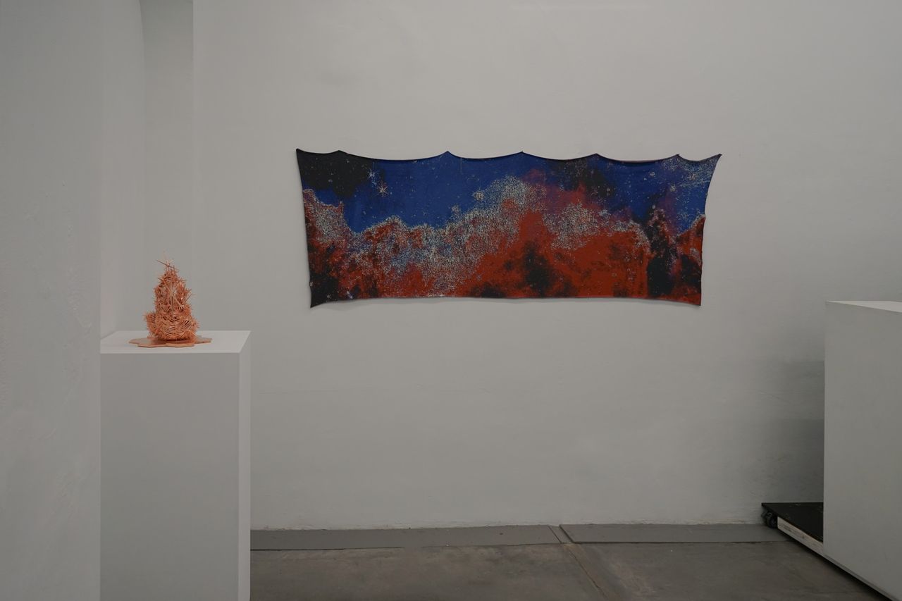 A horizontal cloth tapestry of a space photograph hangs on a white wall.