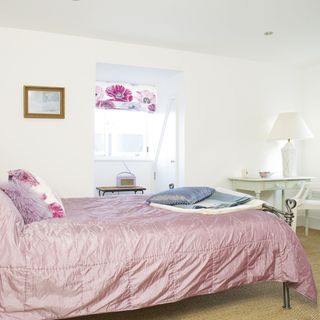 white bedroom with pink bed and lamp light