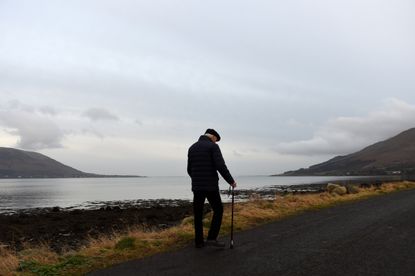 Northern Ireland is seen on the left and the Republic of Ireland is seen on the right with Carlingford Lough in the middle, and an old man walks with a cane along the shore.