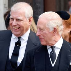 Prince Andrew and The King wearing dark suits and smiling