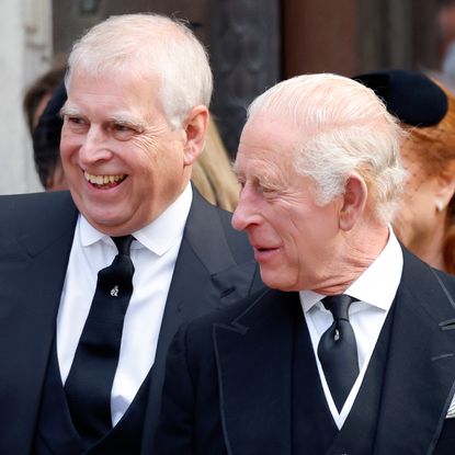 Prince Andrew and The King wearing dark suits and smiling