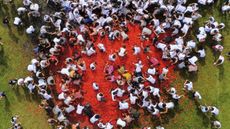 An aerial photograph of a crowd on and around a mass of tomatoes at the annual Gran Tomatina in Sutamarchán, Colombia