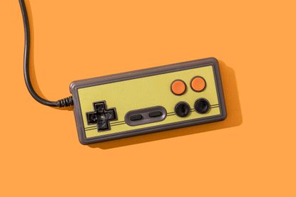 A retro game controller on an orange background