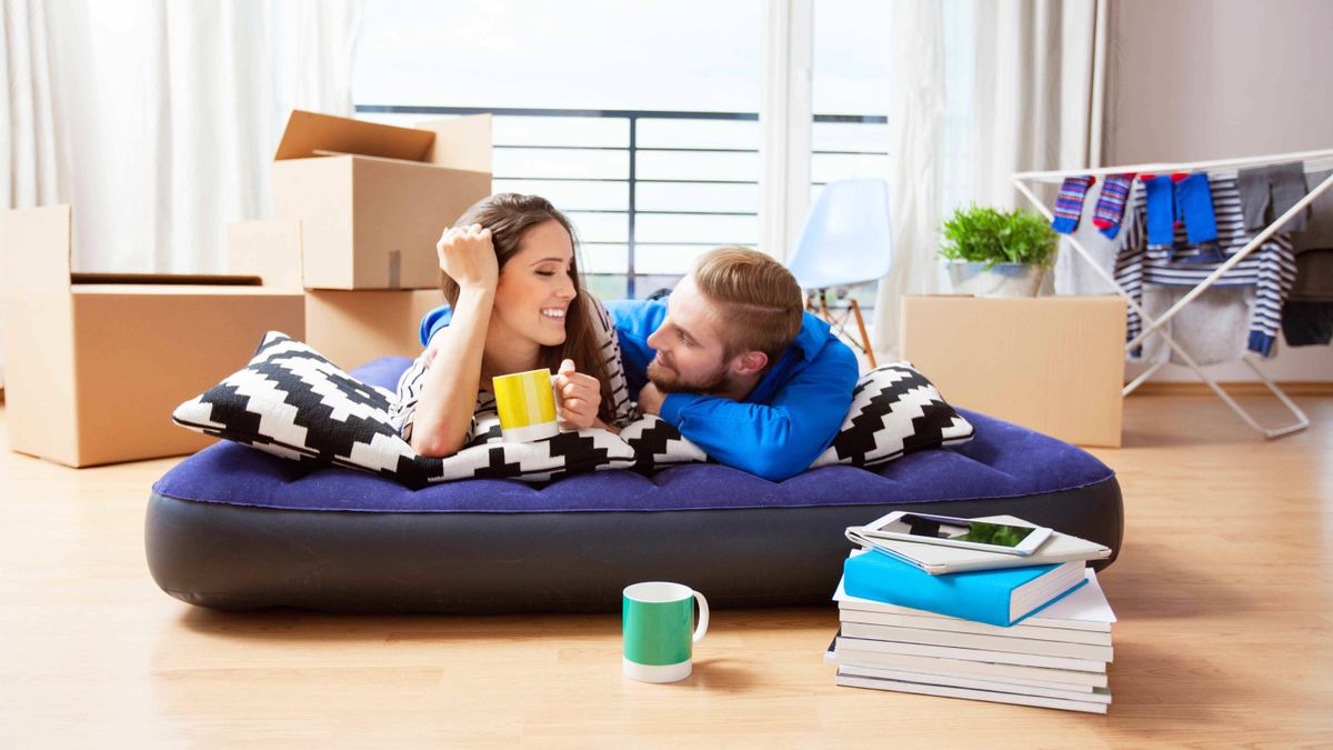 A man and a woman lie and talk on a blow up mattress in their new house