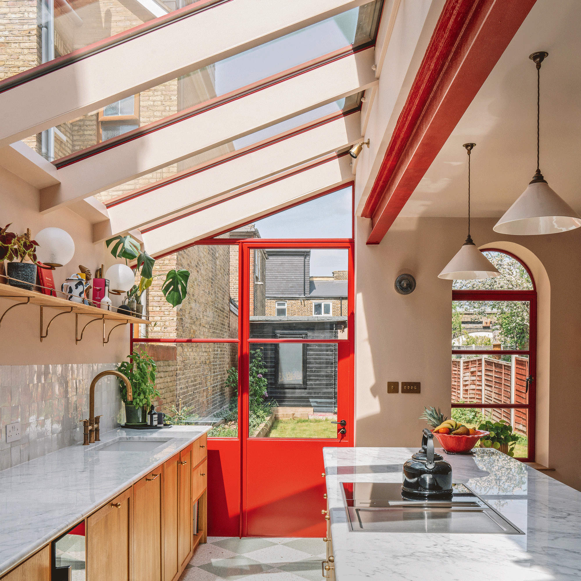 a side return extension kitchen with red patio doors skylight and marble countertops