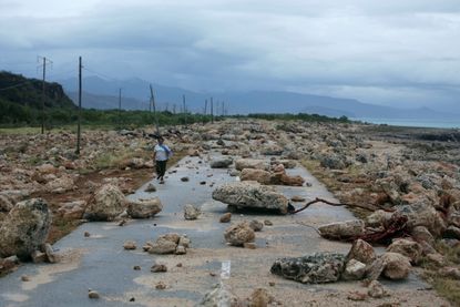 A woman walks on a highway blocked by rocks after the passage of hurricane Matthew on the coast of Guantanamo, Cuba.