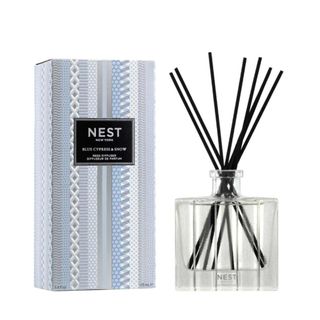 A blue box with a black label next to a reed diffuser with black reeds