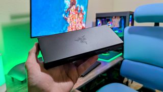 The Razer USB4 Dock being held up by a hand, with the Razer logo highlighted by an overhead light.