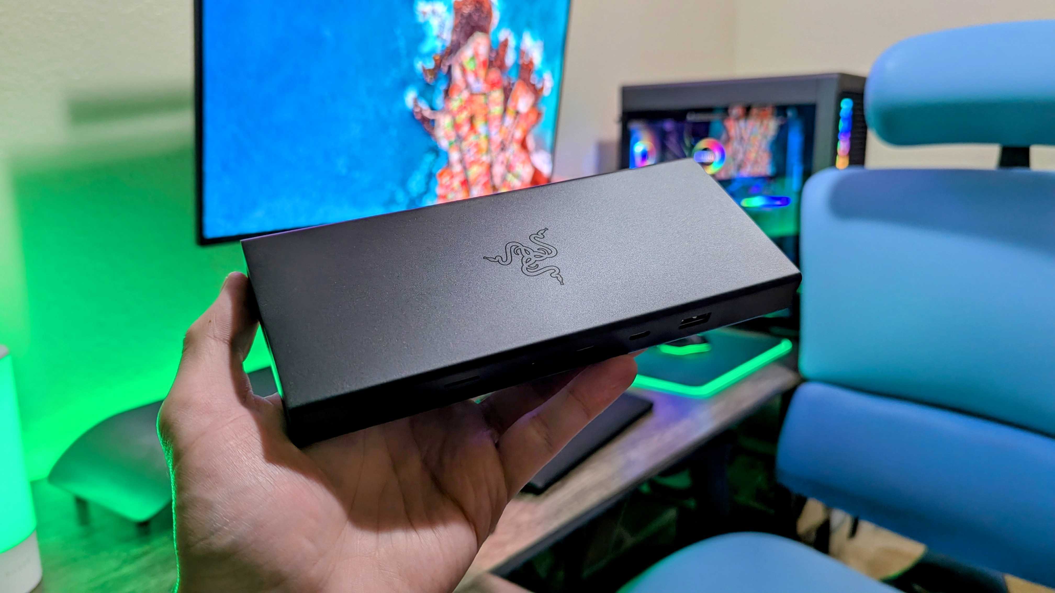 The Razer USB4 Dock being held up by a hand, with the Razer logo highlighted by an overhead light.