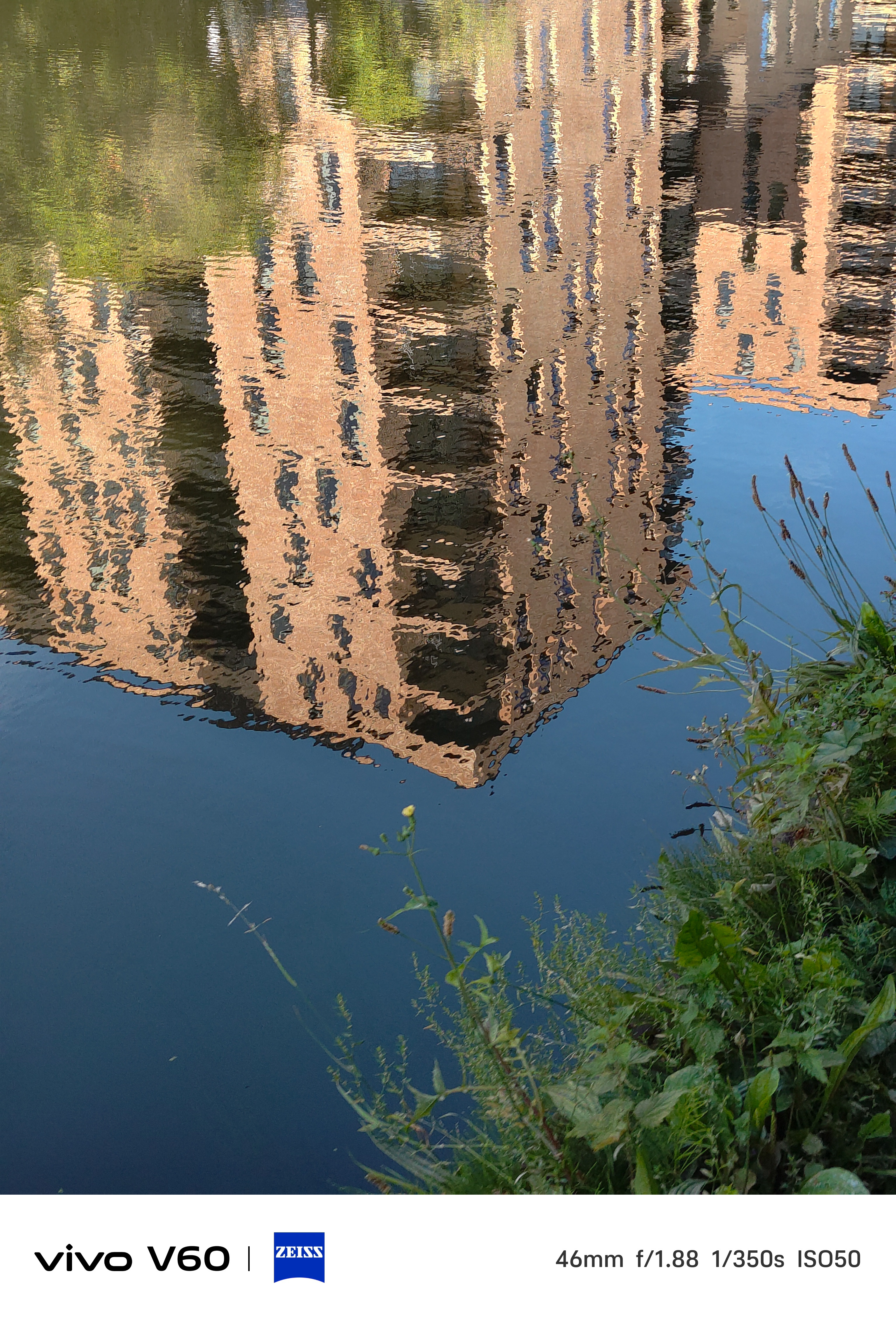 A tall residential building reflected in a river