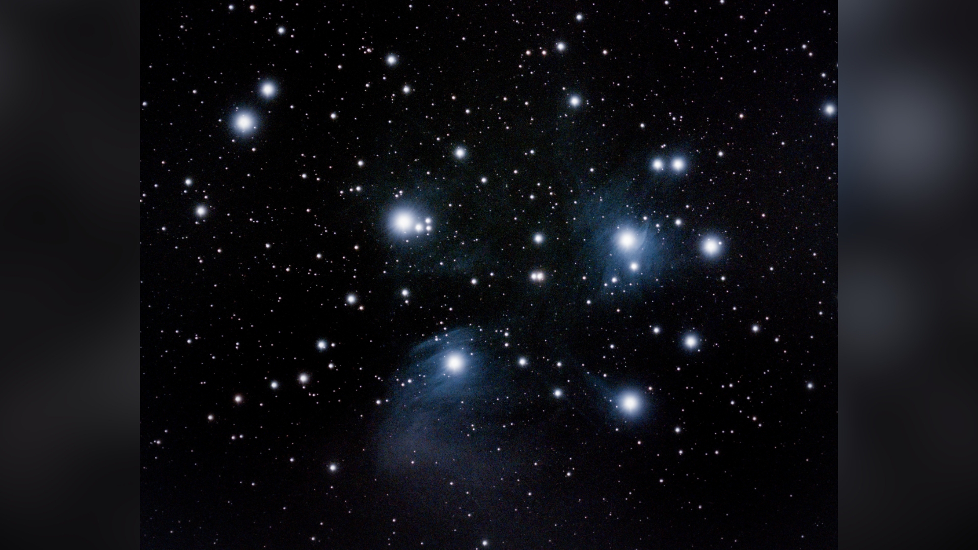a loose cluster of blue stars shrouded in a veil of faint dust