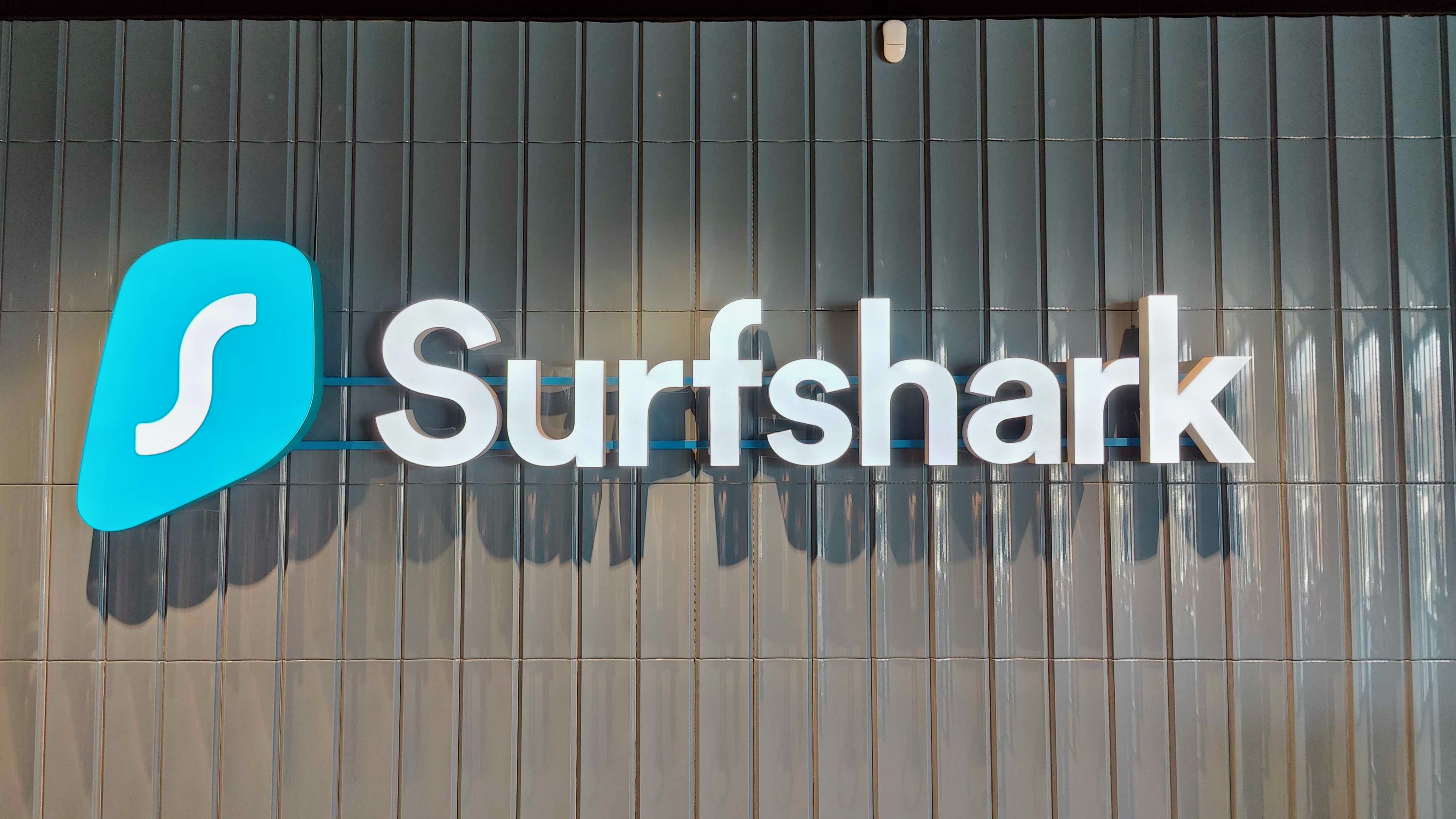 Photograph of a large lit sign featuring the full Surfshark logo