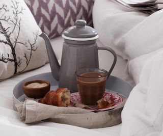 Breakfast in bed. Grey metal enamelled coffee pot, glass, croissant