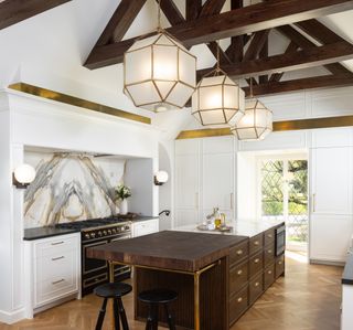 light kitchen cabinets and wood island; tall ceilings with large pendants